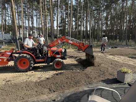 Pracownicy Świata Ogrodów pracują nad wyrównaniem terenu